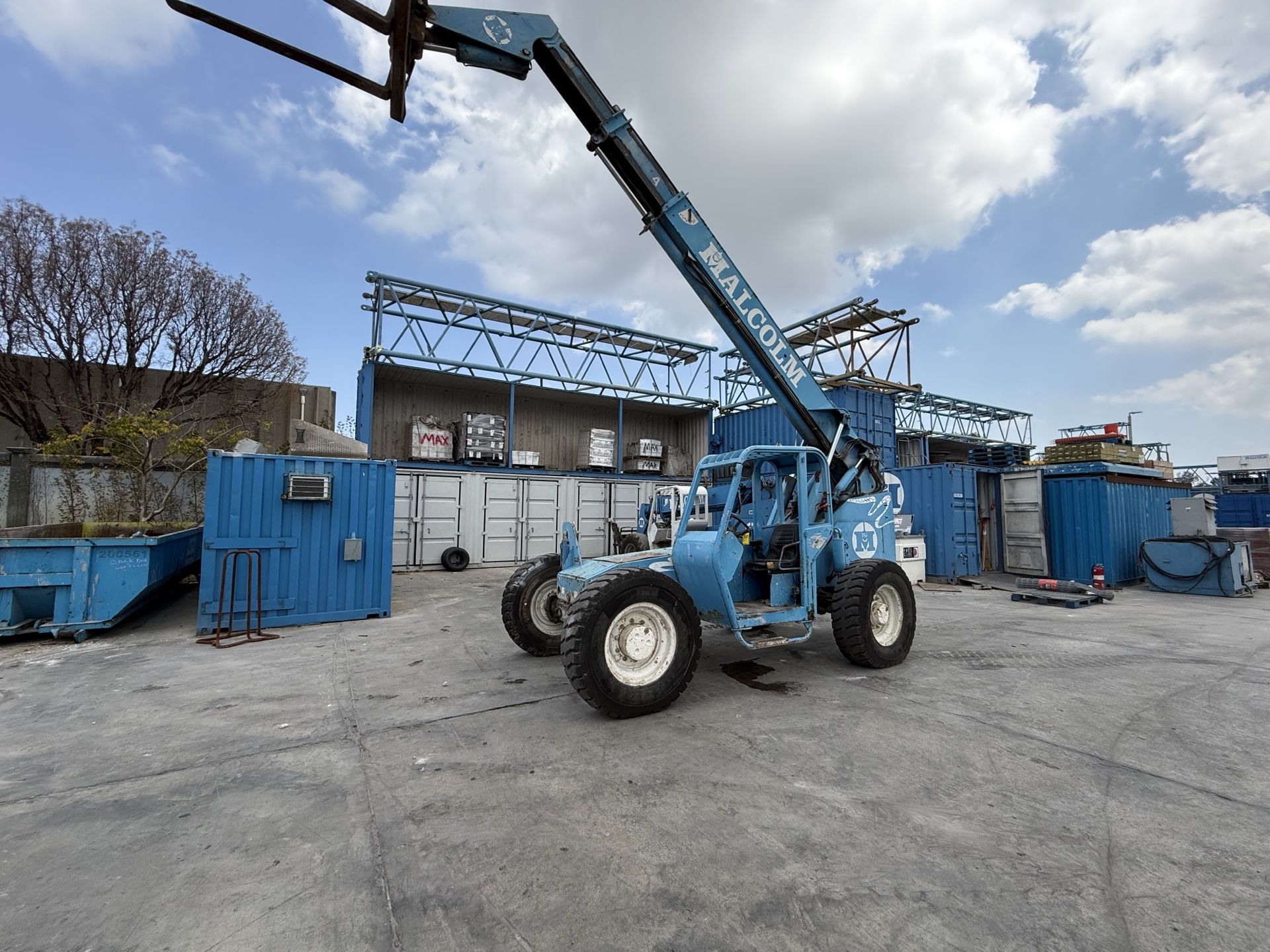 Blue telehandler with raised boom in an industrial yard