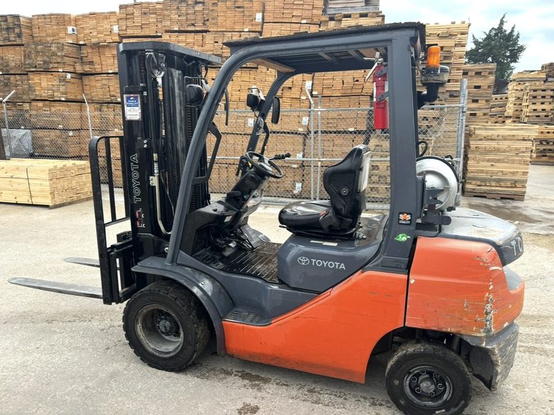Used Toyota LP propane counterbalance forklift parked in a lumber yard, ready for cash purchase and pickup