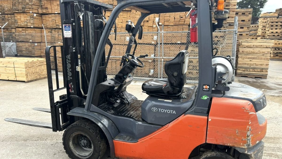 Used Toyota LP propane counterbalance forklift parked in a lumber yard, ready for cash purchase and pickup