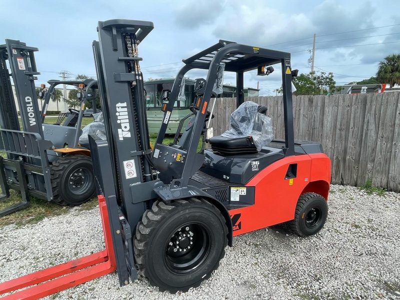 Rough terrain forklifts lined up in a yard alongside other lift trucks awaiting pickup