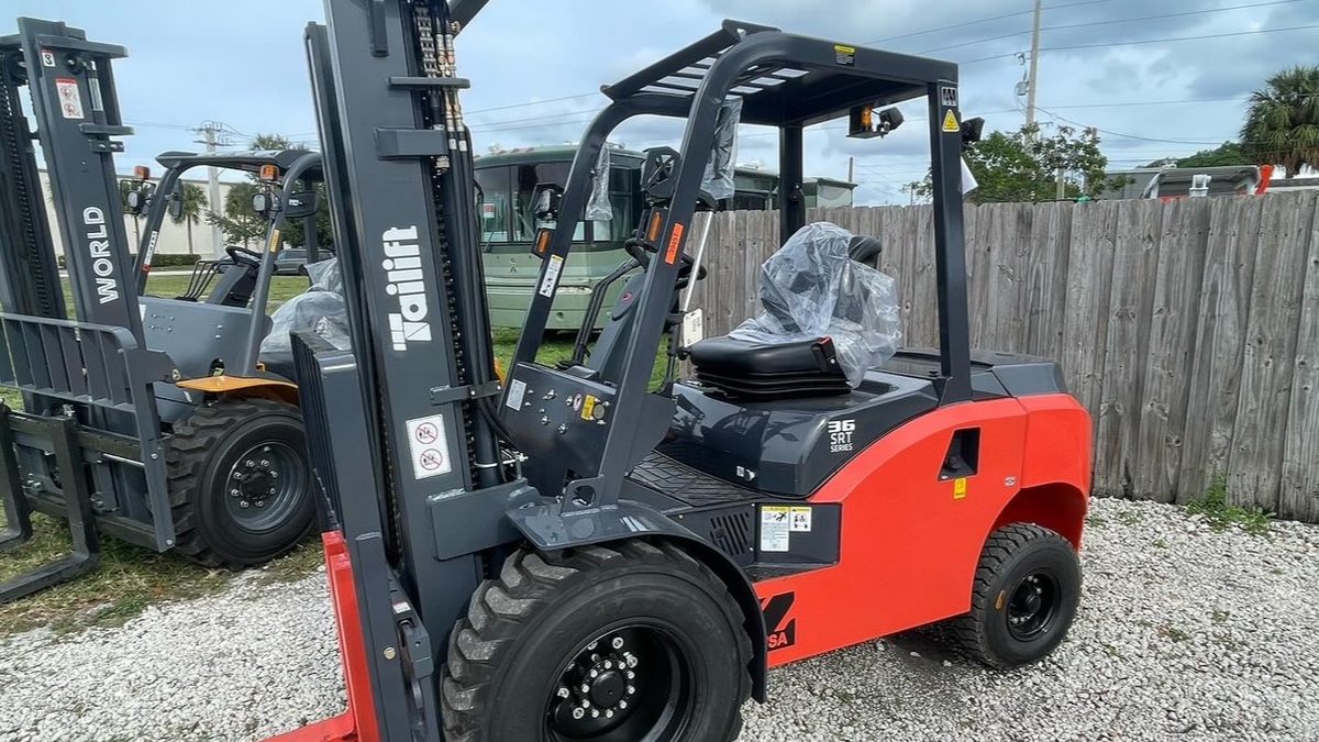Rough terrain forklifts lined up in a yard alongside other lift trucks awaiting pickup