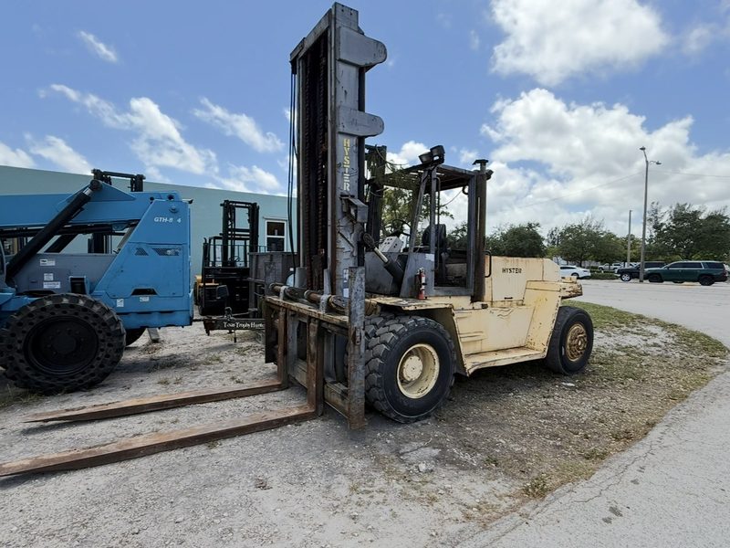 High capacity pneumatic tire forklift with long forks sitting in a surplus yard