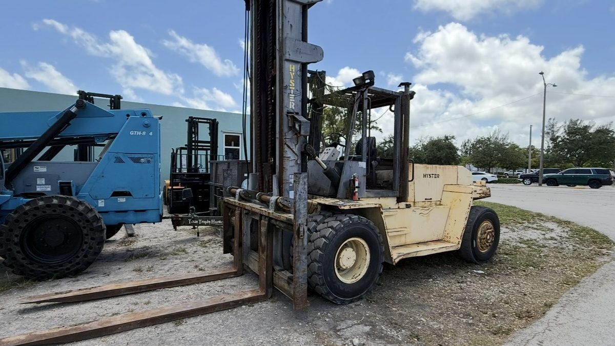 High capacity pneumatic tire forklift with long forks sitting in a surplus yard